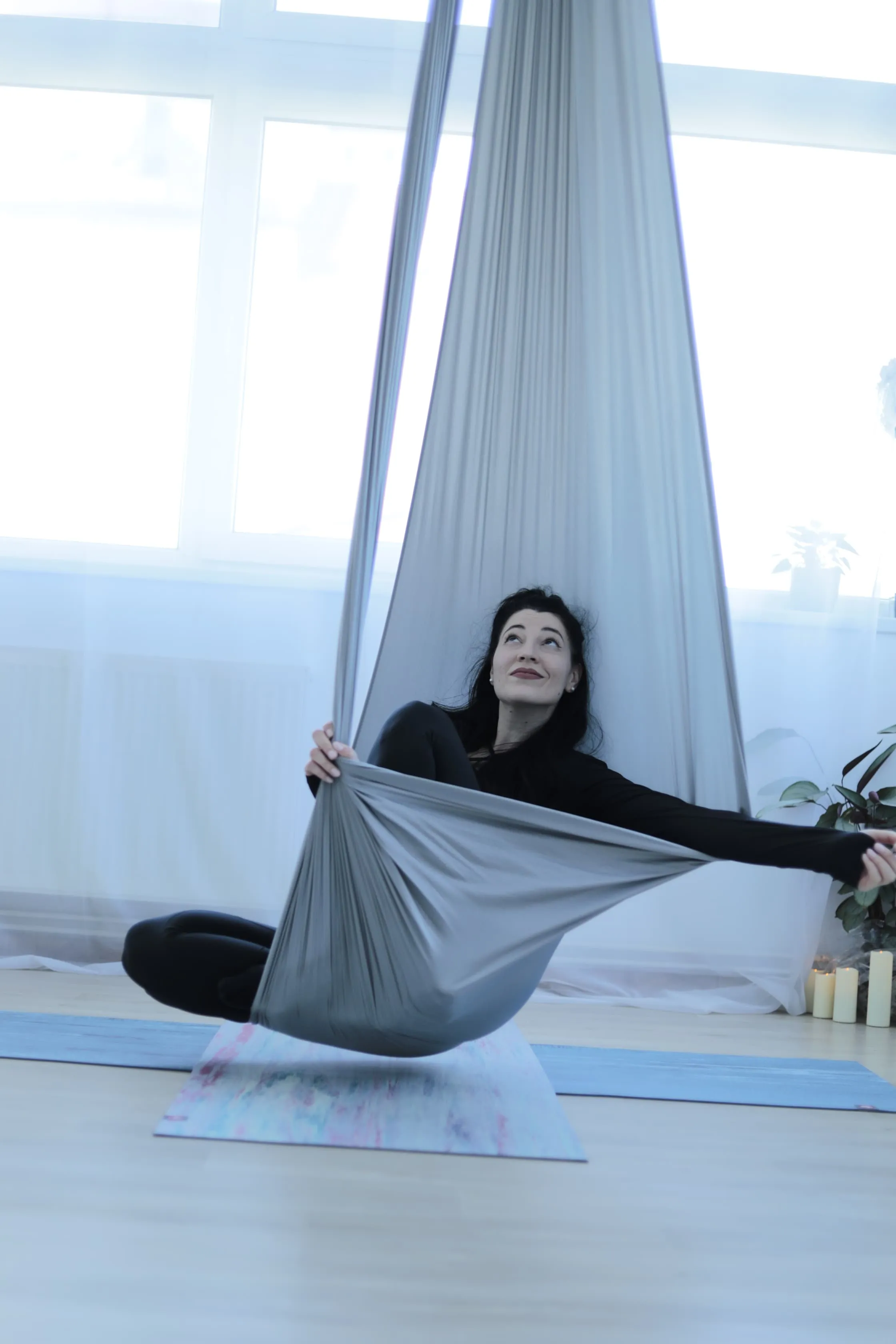 Andreea, instructor de Yin Aerial Yoga, așezată în hamacul gri din studioul din Cluj-Napoca